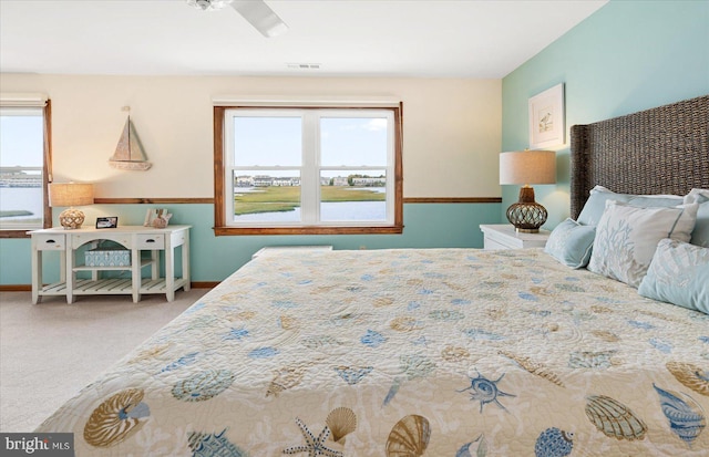 carpeted bedroom featuring multiple windows and ceiling fan