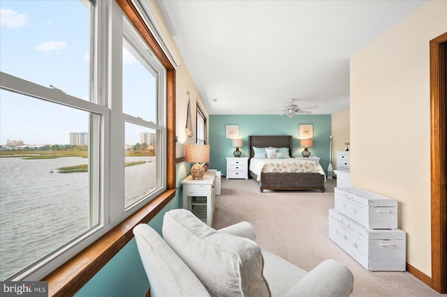 bedroom with a water view, ceiling fan, and light carpet