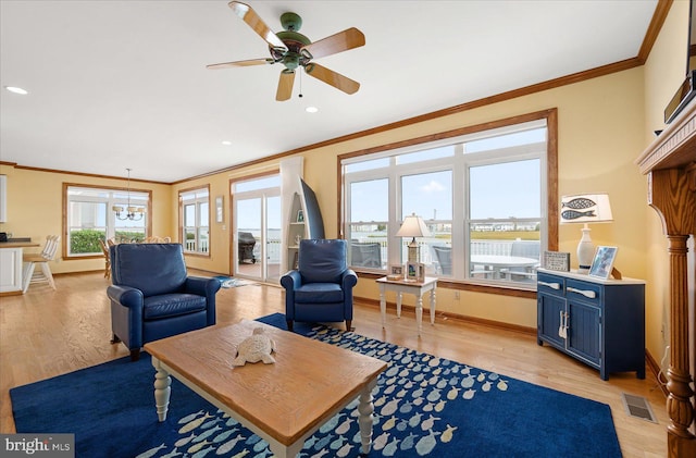 living room featuring ornamental molding, light hardwood / wood-style flooring, and ceiling fan with notable chandelier