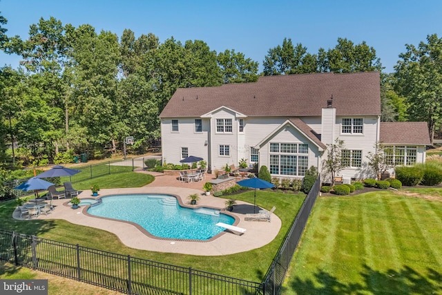 view of pool with a diving board, a lawn, and a patio