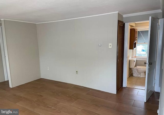 unfurnished bedroom featuring ensuite bathroom and crown molding