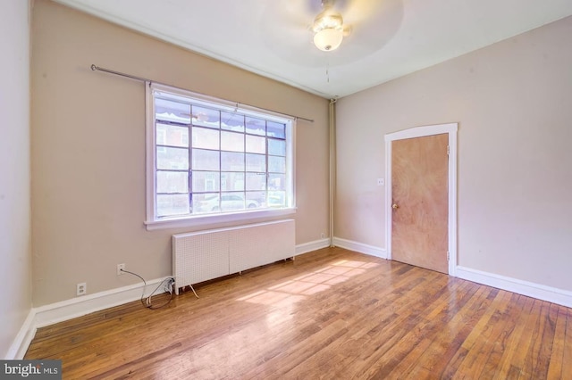 spare room featuring ceiling fan, radiator, and wood-type flooring