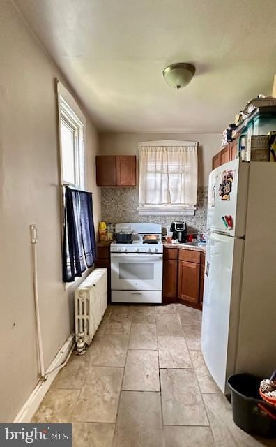 kitchen with radiator, white appliances, a wealth of natural light, and decorative backsplash