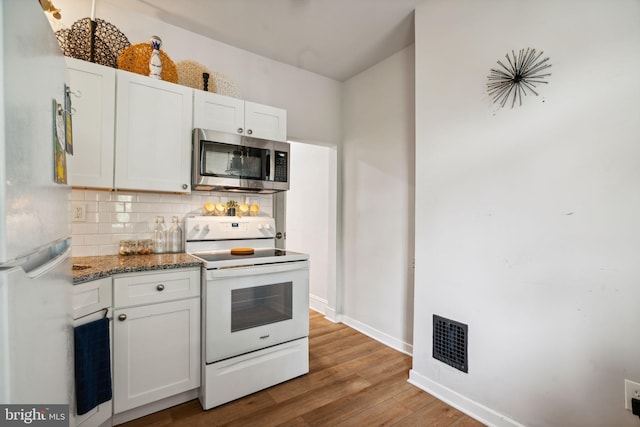 kitchen with white appliances, visible vents, light wood-style flooring, white cabinetry, and tasteful backsplash