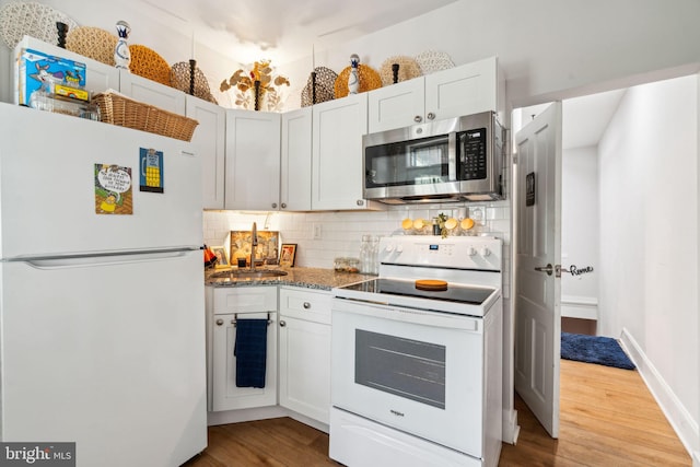 kitchen with stone countertops, white appliances, backsplash, and wood finished floors