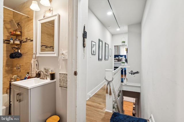 hallway with a sink, baseboards, and light wood finished floors