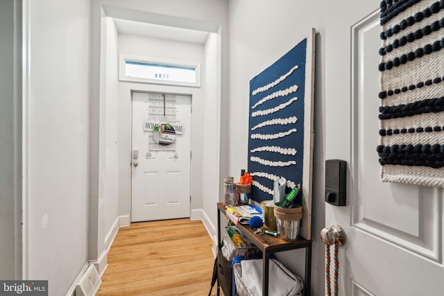 doorway to outside with light wood finished floors, visible vents, and baseboards