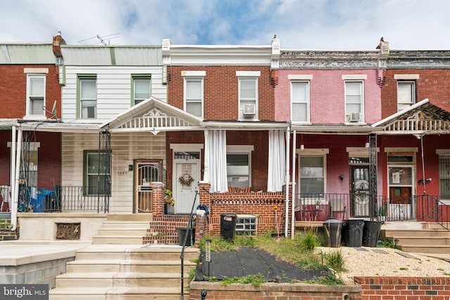 townhome / multi-family property featuring brick siding and covered porch