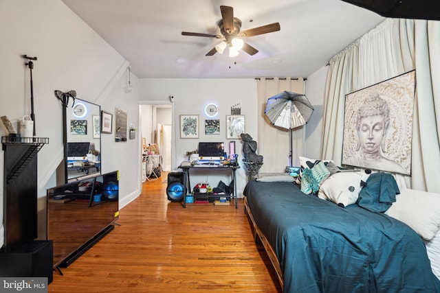 bedroom with ceiling fan, baseboards, and wood finished floors