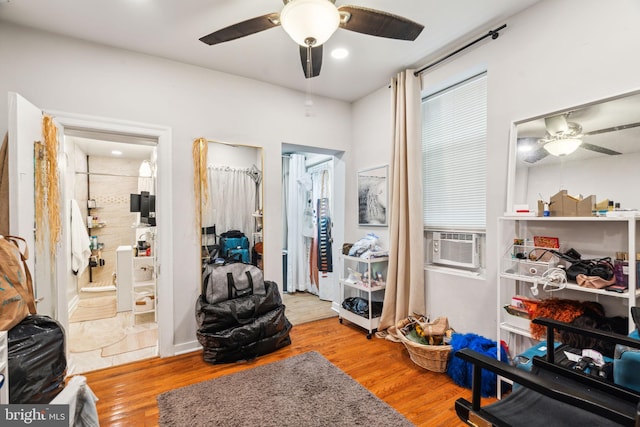 interior space featuring a ceiling fan, ensuite bath, cooling unit, and wood finished floors