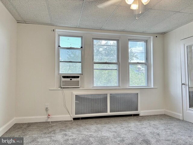 carpeted spare room featuring ceiling fan, cooling unit, a paneled ceiling, and radiator heating unit