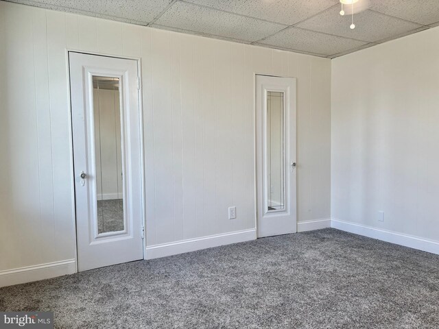 empty room with carpet flooring, ceiling fan, and a drop ceiling