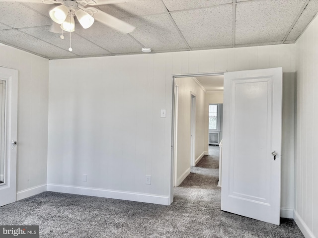 carpeted spare room featuring a drop ceiling and ceiling fan