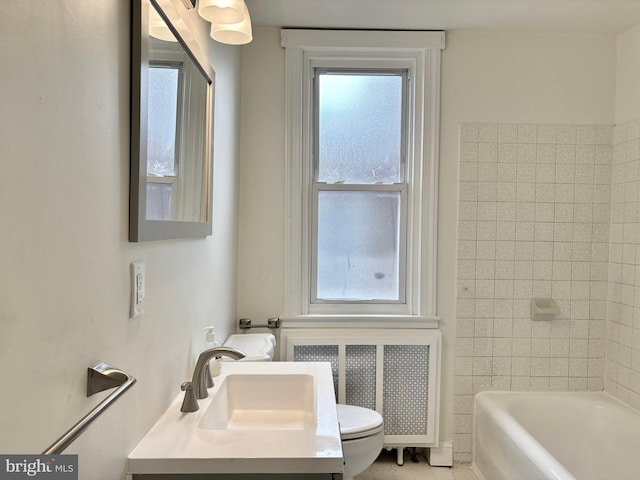 bathroom with vanity, toilet, radiator heating unit, and a tub