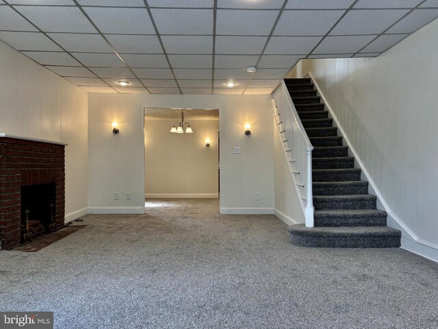 unfurnished living room featuring a chandelier, carpet floors, a fireplace, and a paneled ceiling