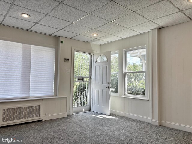 foyer entrance featuring a drop ceiling, radiator, carpet, and plenty of natural light