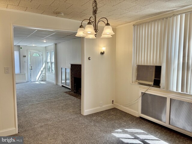 unfurnished dining area with a brick fireplace, a chandelier, carpet flooring, and cooling unit