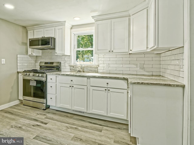 kitchen with appliances with stainless steel finishes, tasteful backsplash, light hardwood / wood-style flooring, and white cabinets