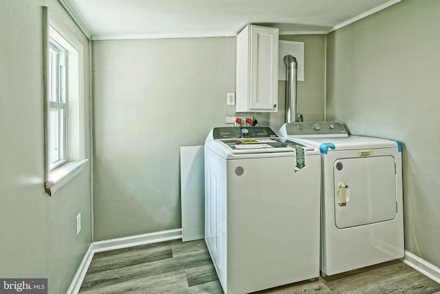 laundry area with crown molding, light hardwood / wood-style floors, independent washer and dryer, and cabinets