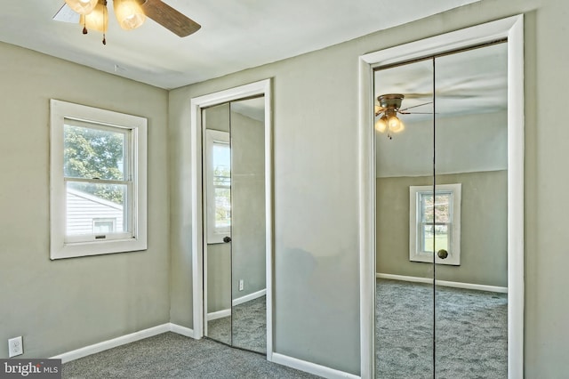 unfurnished bedroom featuring ceiling fan, multiple windows, and carpet floors