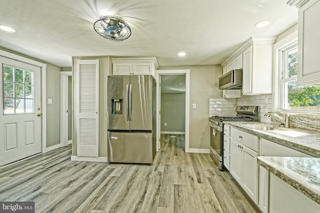 kitchen featuring appliances with stainless steel finishes, light hardwood / wood-style flooring, and white cabinets