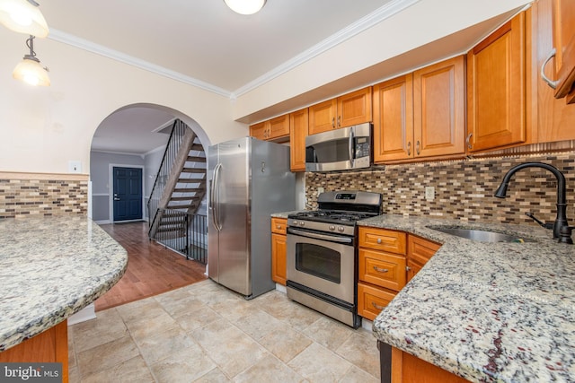 kitchen featuring ornamental molding, stainless steel appliances, light stone counters, and sink