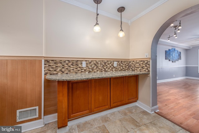 kitchen with decorative backsplash, light stone counters, pendant lighting, light hardwood / wood-style flooring, and ornamental molding