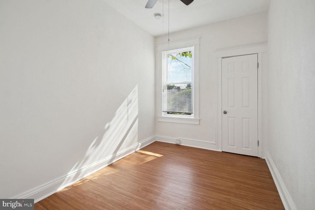 empty room featuring wood finished floors, baseboards, and ceiling fan