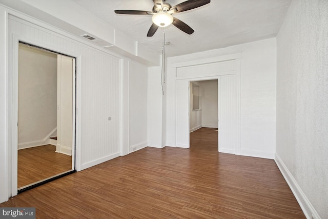 empty room with visible vents, stairs, ceiling fan, and wood finished floors