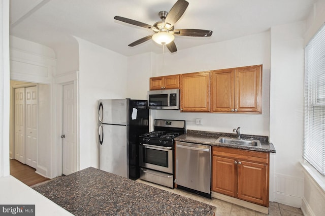 kitchen with brown cabinets, stainless steel appliances, ceiling fan, and a sink