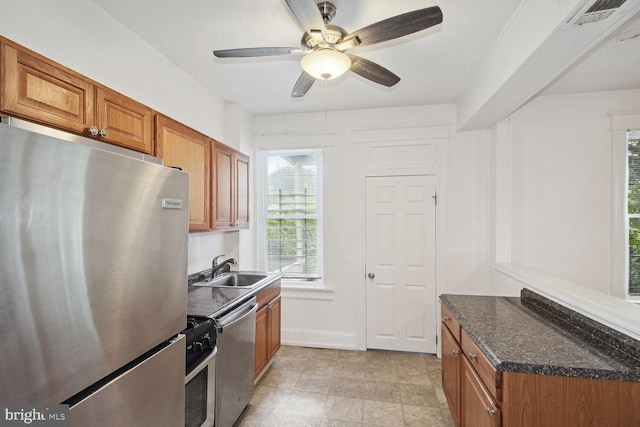 kitchen featuring dark stone countertops, brown cabinetry, visible vents, a sink, and stainless steel appliances