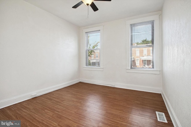 empty room with a wealth of natural light, visible vents, baseboards, and wood finished floors