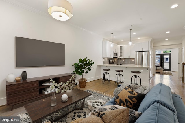 living room featuring crown molding, sink, and light hardwood / wood-style floors