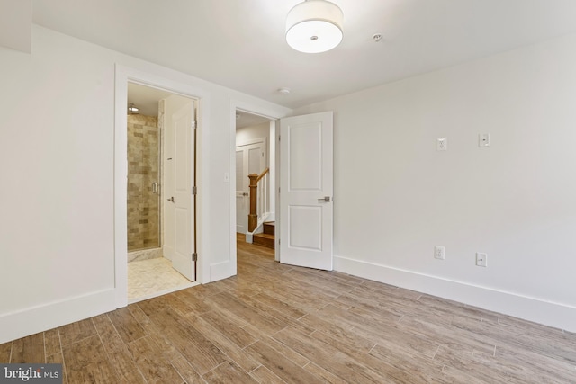 unfurnished bedroom featuring light wood-type flooring and connected bathroom