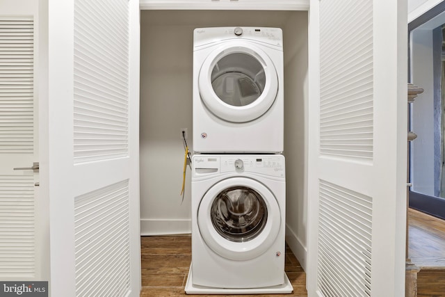 laundry area with hardwood / wood-style floors and stacked washer and dryer