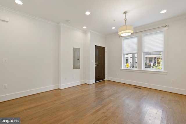 empty room with electric panel, crown molding, and light wood-type flooring