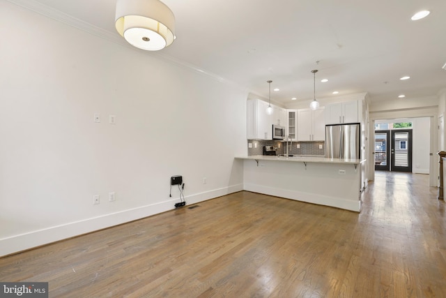 kitchen with decorative light fixtures, wood-type flooring, a breakfast bar, stainless steel appliances, and white cabinetry