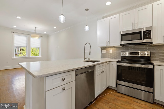 kitchen with stainless steel appliances, light hardwood / wood-style floors, white cabinetry, sink, and kitchen peninsula