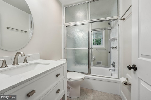 full bathroom featuring combined bath / shower with glass door, vanity, toilet, and tile patterned floors