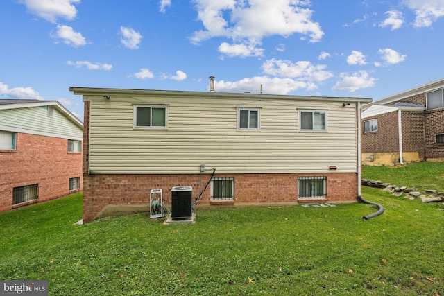 back of property with central AC unit and a yard