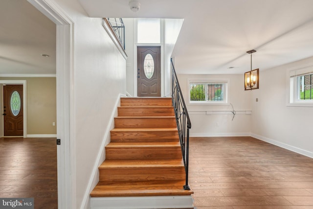 stairway featuring ornamental molding, a notable chandelier, and hardwood / wood-style floors