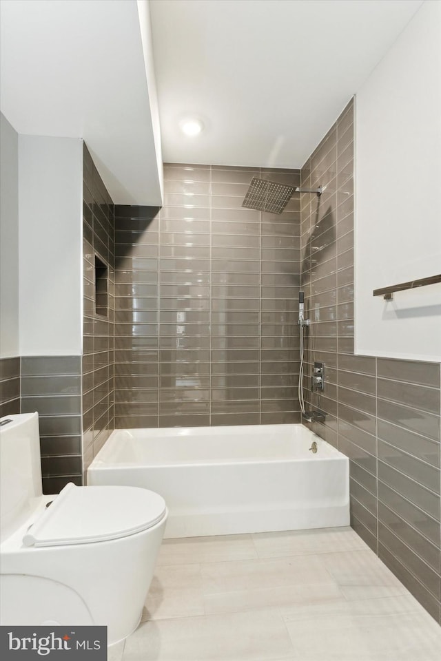 bathroom with tile walls, toilet, and tiled shower / bath combo