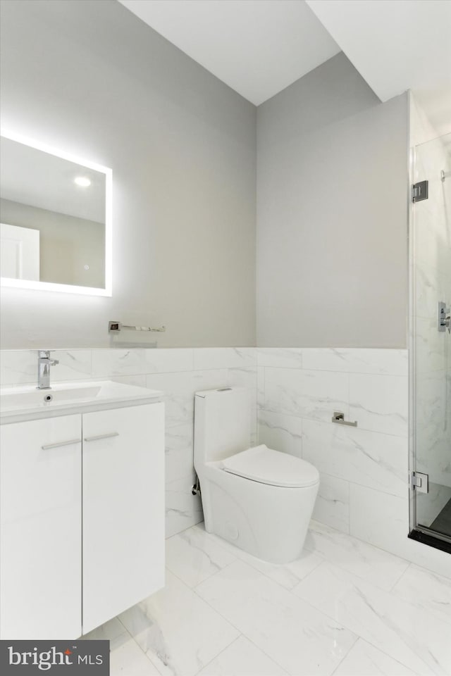 bathroom featuring vanity, toilet, tile walls, and a shower with shower door