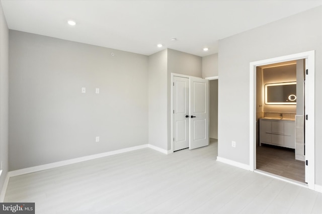 unfurnished bedroom featuring ensuite bath and light wood-type flooring