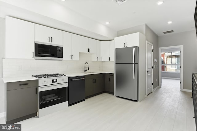 kitchen with gray cabinetry, black dishwasher, stainless steel refrigerator, white gas range oven, and white cabinetry