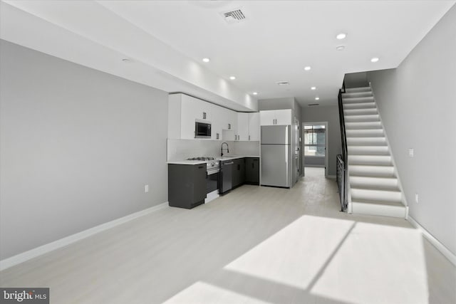 kitchen with stainless steel fridge, white cabinetry, light hardwood / wood-style flooring, and sink