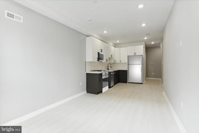 kitchen with light wood-type flooring, white cabinets, stainless steel appliances, and tasteful backsplash