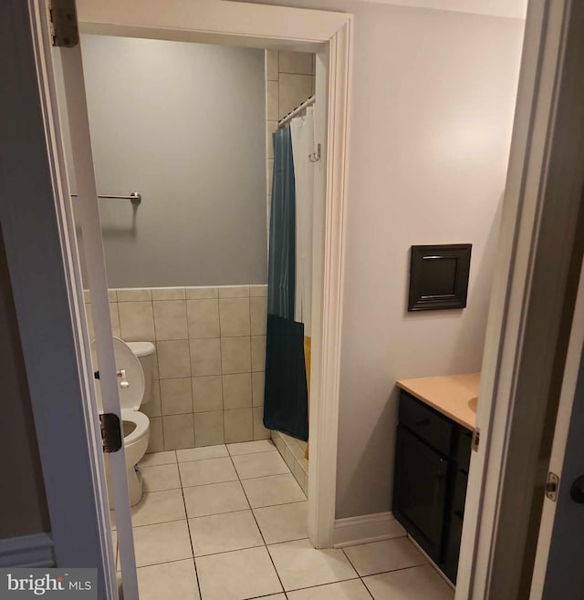 bathroom with vanity, tile patterned floors, a shower with curtain, toilet, and tile walls