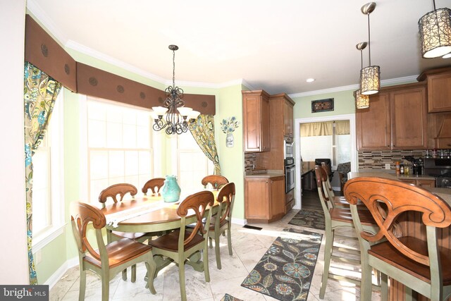 dining space featuring plenty of natural light, crown molding, and a chandelier