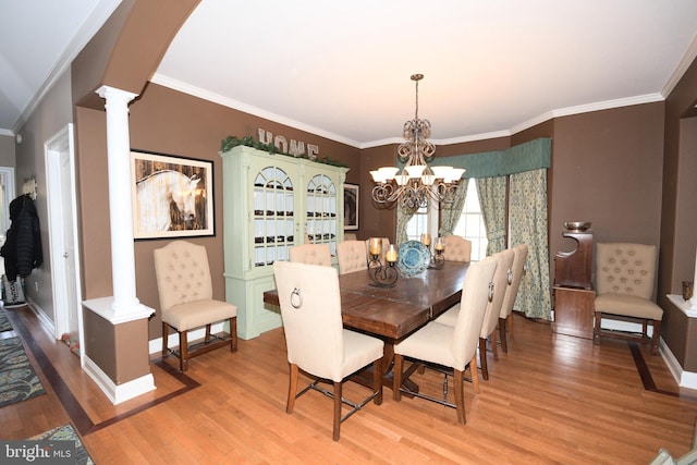 dining room featuring hardwood / wood-style floors, ornate columns, crown molding, and a chandelier